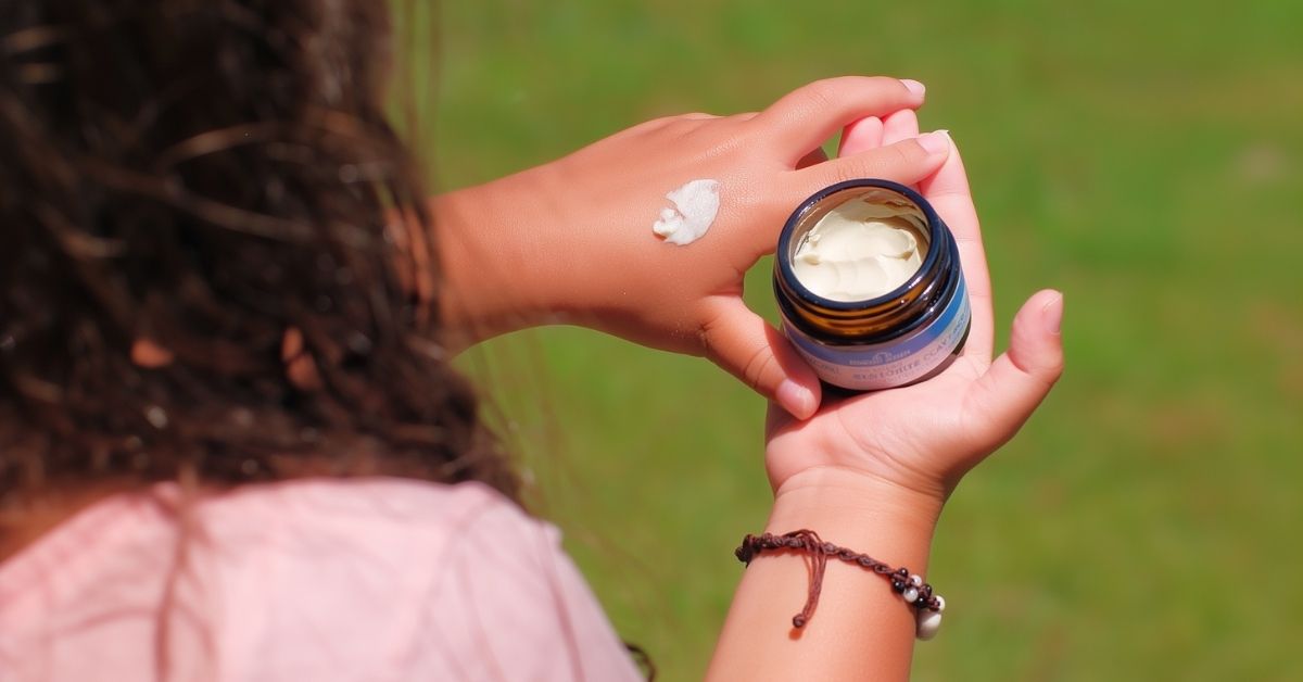 Doğal bir ortamda eline krem süren çocuk, mikrobiyomu destekleyen nazik cilt bakımını temsil ediyor